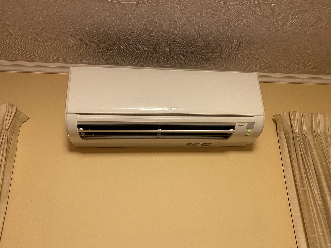 Unidad exterior de aerotermia instalada en la pared de una vivienda