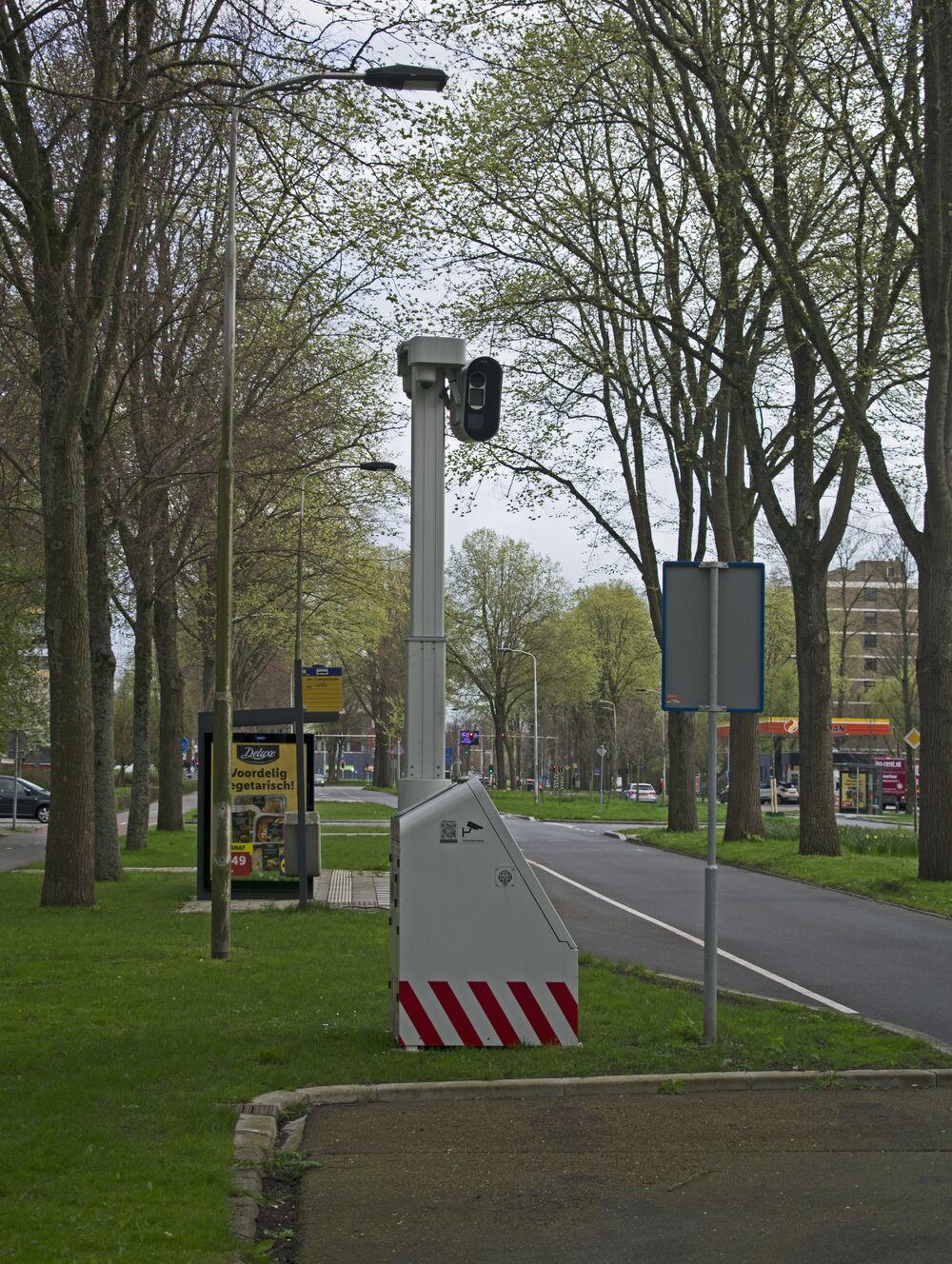 Radar fijo de velocidad junto a una avenida arbolada