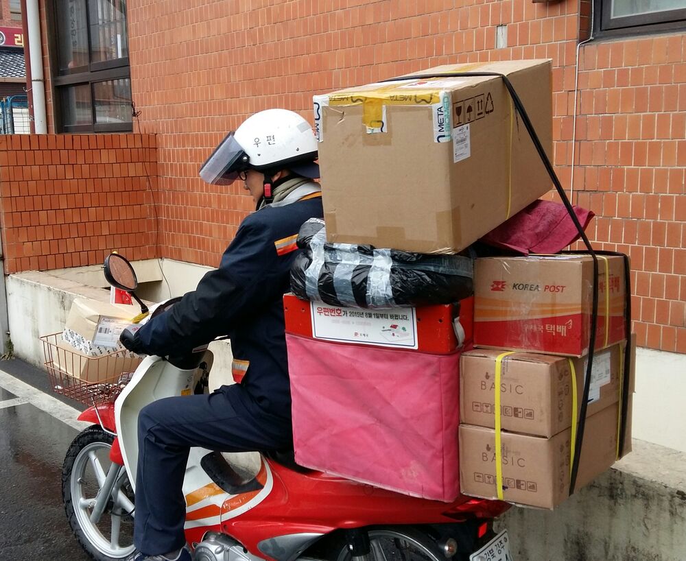 Repartidor postal en moto cargado de paquetes