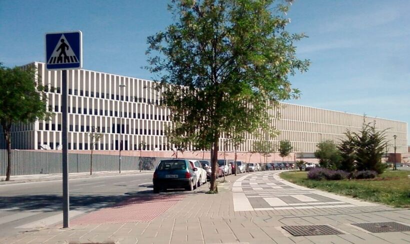 Edificio de una ciudad de la justicia, con fachada alargada de lamas verticales y la calle en primer plano