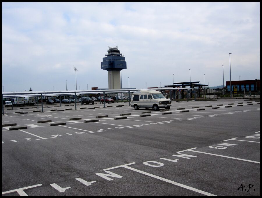 Aparcamiento exterior de superficie con coches estacionados en filas