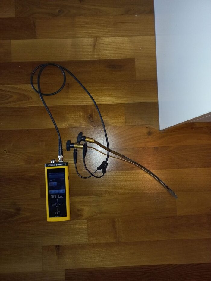 Medidor de humedad con sondas apoyado sobre un suelo de madera